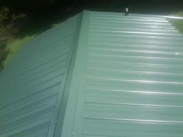 New green metal panels meeting at the ridge of a roof — Flat Roof Repair work by our crew in Davy