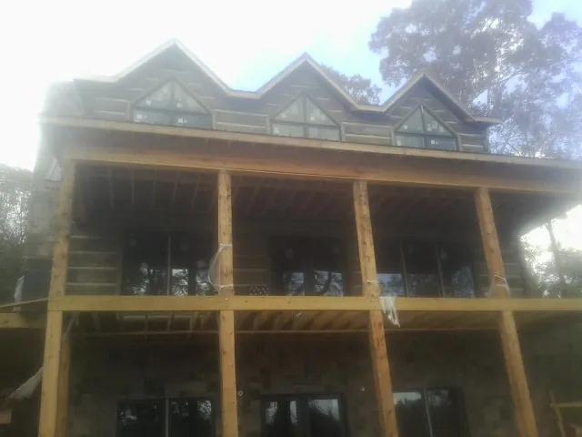 Dormers and porch framing on a large log home under construction — Roof Coating work by our crew in Davy