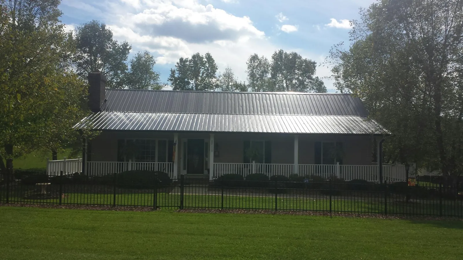 Gray metal roof on a brick ranch with a full width front porch — Gutter Guard Installation work by our crew in Davy