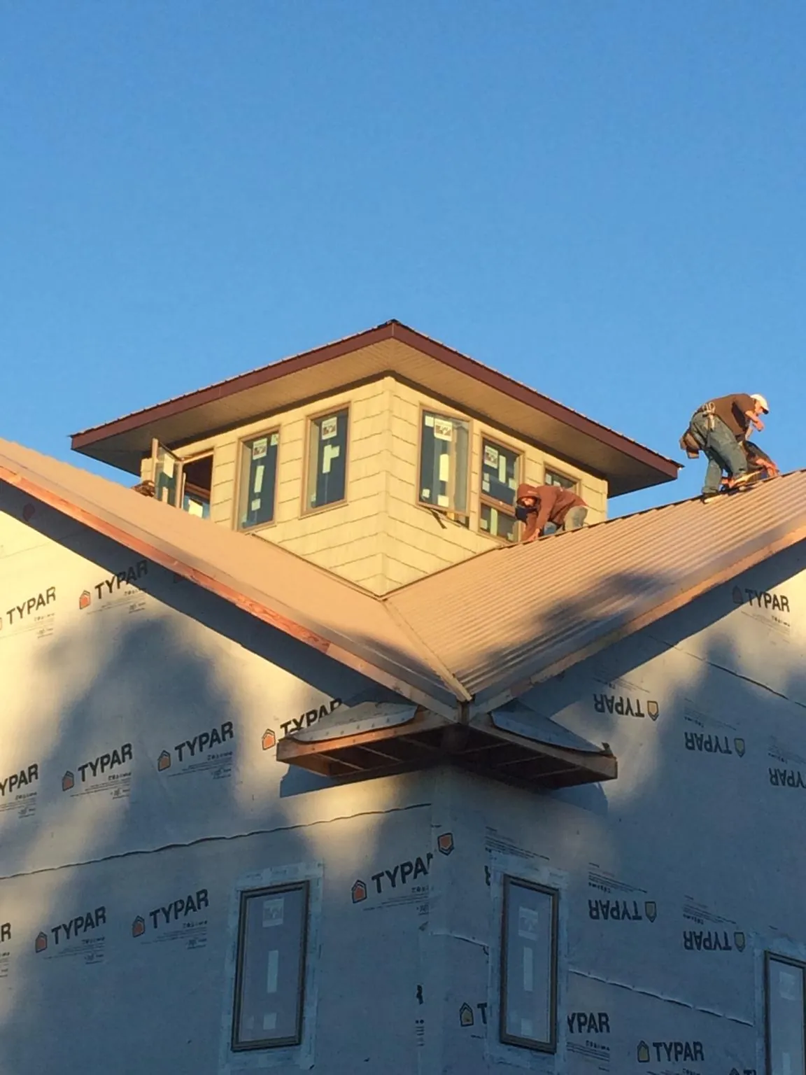Roofers working around a rooftop cupola on a new metal roof at sunset — Roof Waterproofing in Davy by Roofing Brothers